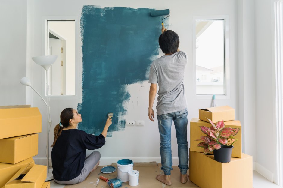The couple paints the wall in the house